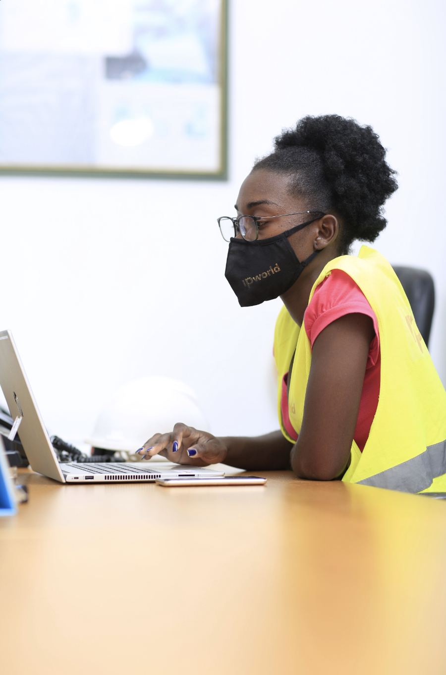 IP World technician working on a laptop, wearing the company's mask and vest